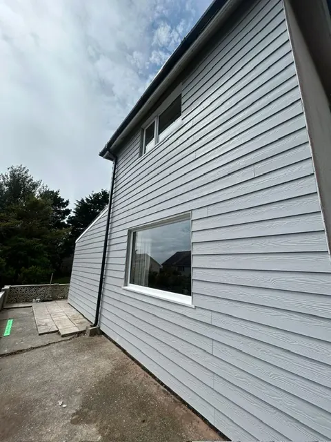 Side wall of a house clad in grey boards. One of our jobs.